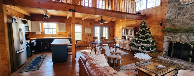 living room featuring wood walls, ceiling fan, a fireplace, and dark hardwood / wood-style floors