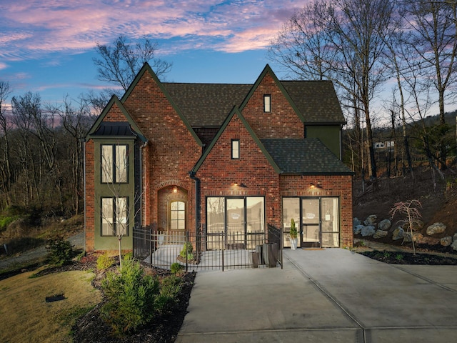 view of front of home with brick siding, concrete driveway, and a shingled roof