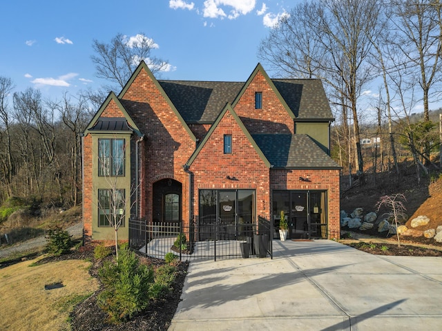 view of front of house featuring brick siding and roof with shingles