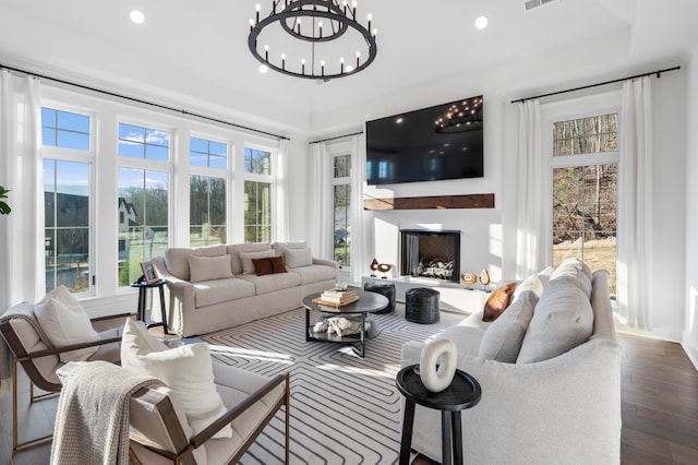 living room with a wealth of natural light, dark wood-type flooring, and a chandelier