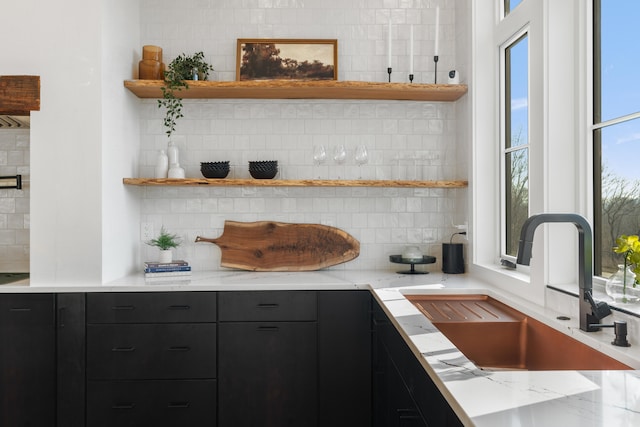 kitchen with tasteful backsplash, sink, and light stone countertops