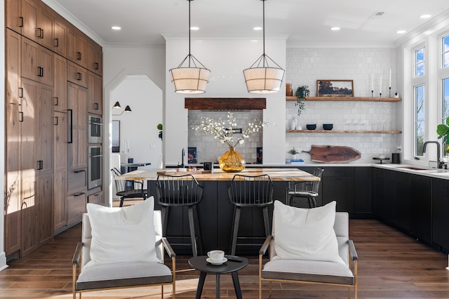 kitchen featuring ornamental molding, a kitchen bar, a center island, and dark hardwood / wood-style floors