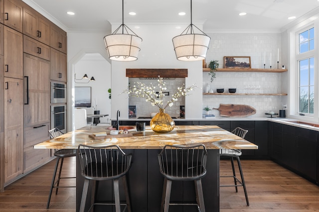 kitchen featuring hardwood / wood-style floors, crown molding, tasteful backsplash, a center island, and a breakfast bar area