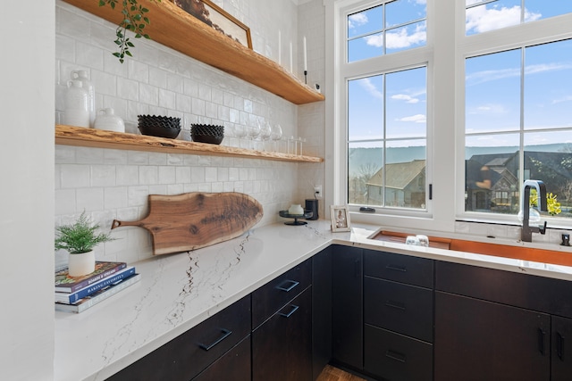 kitchen featuring a wealth of natural light, light stone counters, and tasteful backsplash