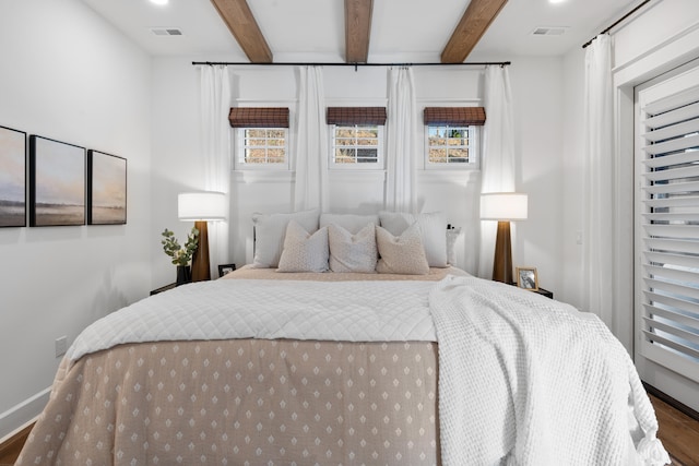 bedroom with multiple windows, beamed ceiling, and dark hardwood / wood-style floors