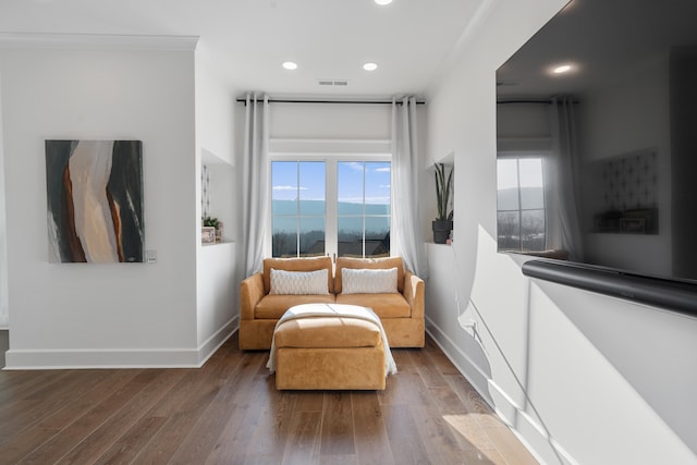 sitting room featuring a water view, hardwood / wood-style flooring, and crown molding