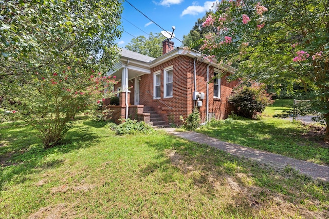 view of home's exterior featuring a lawn, brick siding, and a chimney