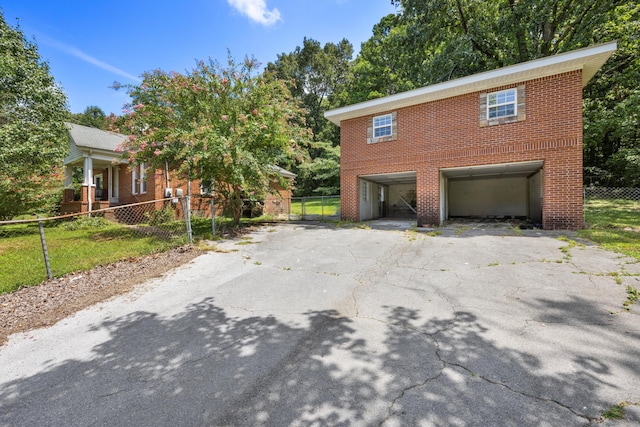 view of front of home featuring fence, an attached garage, brick siding, and aphalt driveway