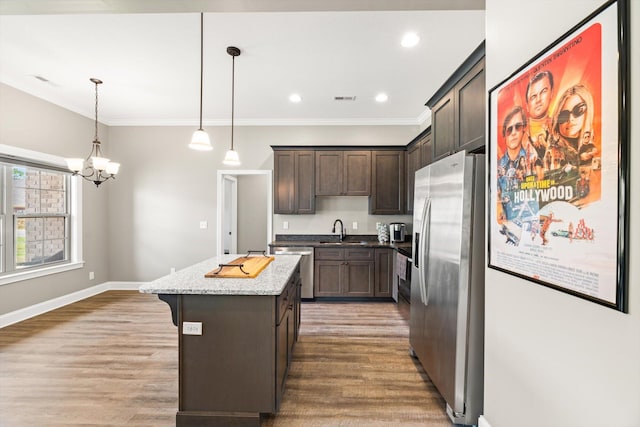 kitchen featuring hardwood / wood-style floors, light stone counters, stainless steel appliances, sink, and a kitchen island