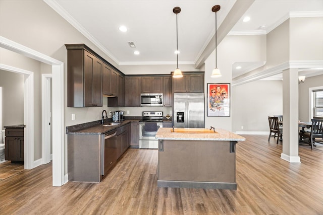 kitchen with hardwood / wood-style flooring, a center island, stone counters, stainless steel appliances, and sink