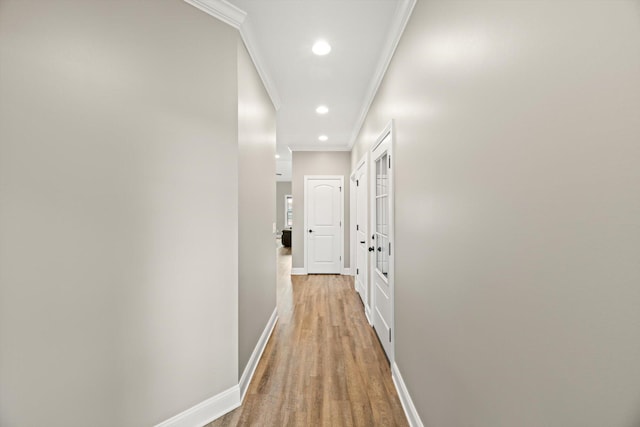 corridor featuring light wood-type flooring, crown molding, baseboards, and recessed lighting