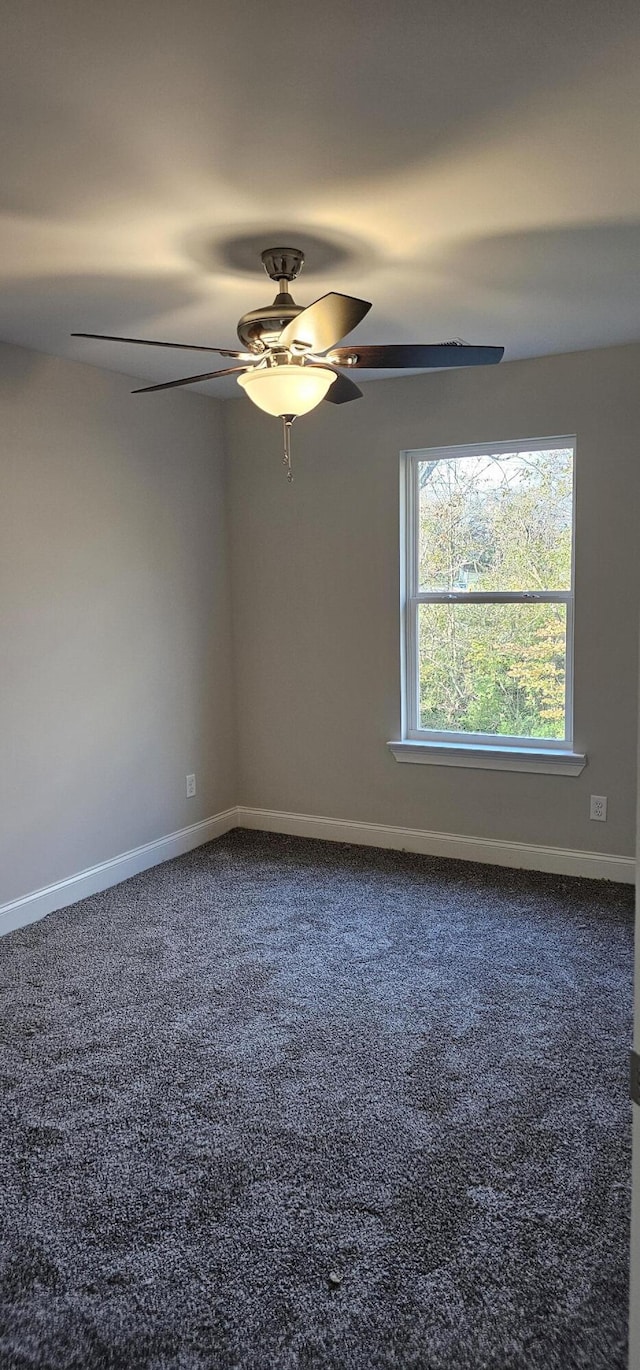 carpeted spare room with ceiling fan and baseboards