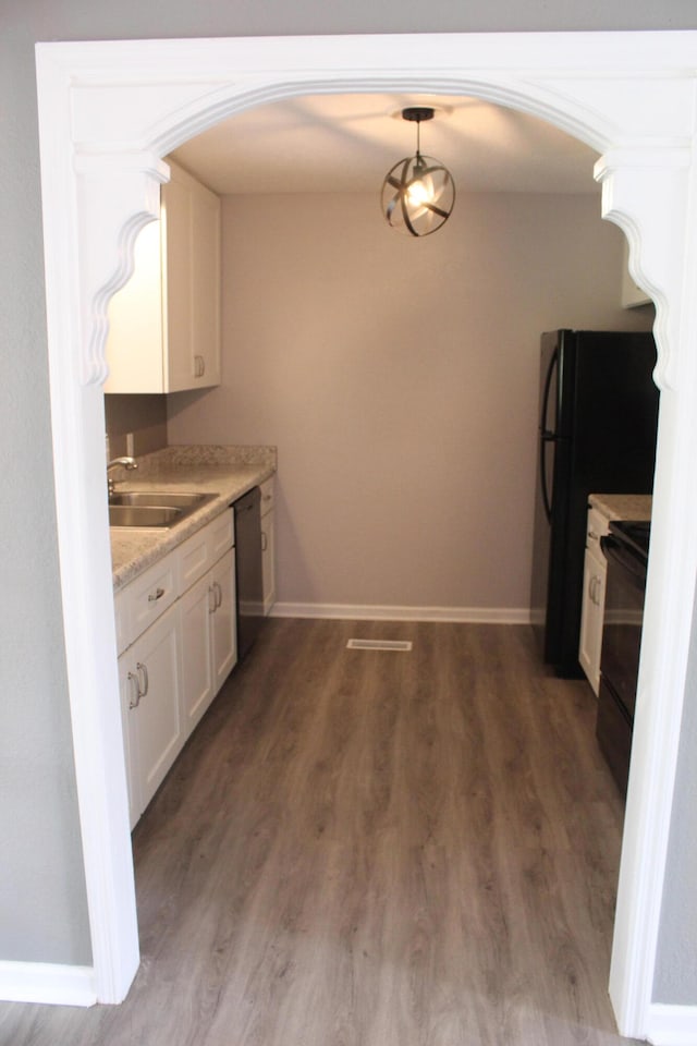 kitchen featuring white cabinetry, decorative light fixtures, black appliances, sink, and dark wood-type flooring