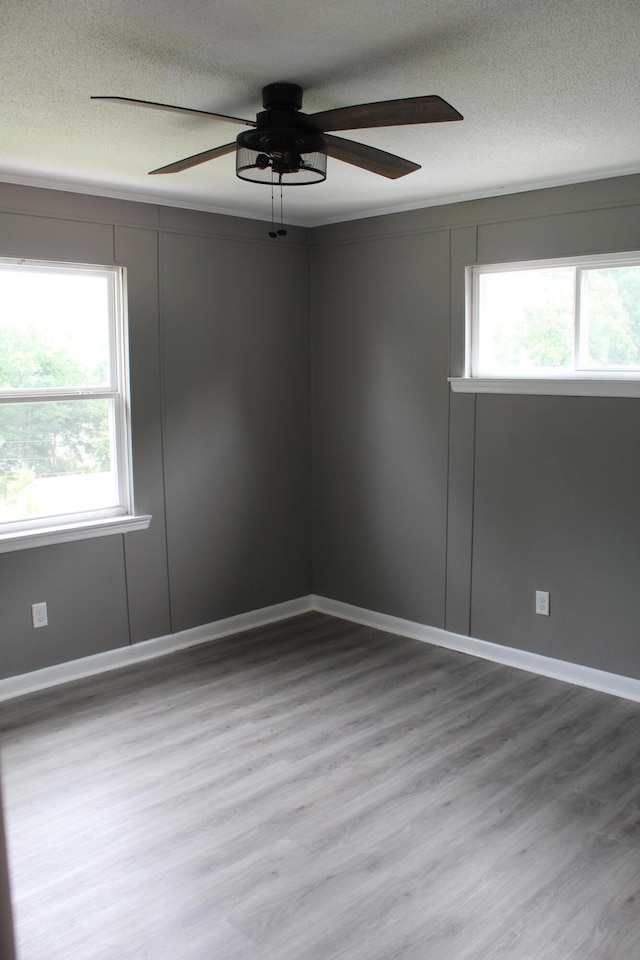 spare room with a wealth of natural light, ceiling fan, wood-type flooring, and a textured ceiling