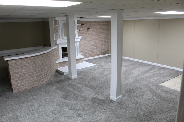 basement featuring brick wall, a paneled ceiling, and carpet floors