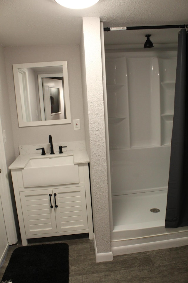 bathroom featuring a shower, wood-type flooring, a textured ceiling, and vanity