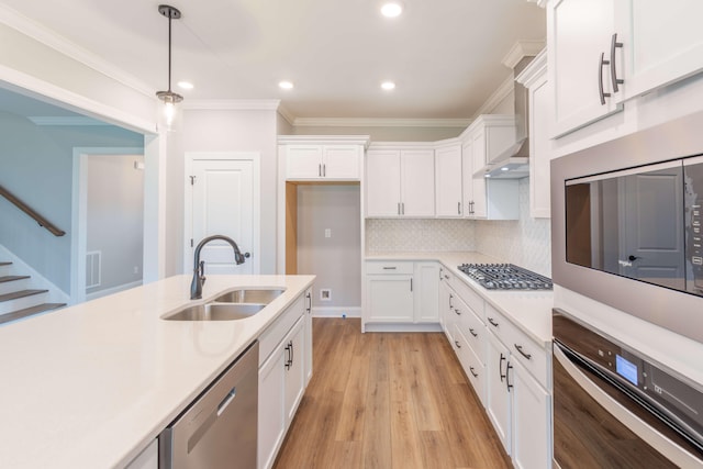 kitchen with white cabinets, pendant lighting, stainless steel appliances, light wood-type flooring, and sink