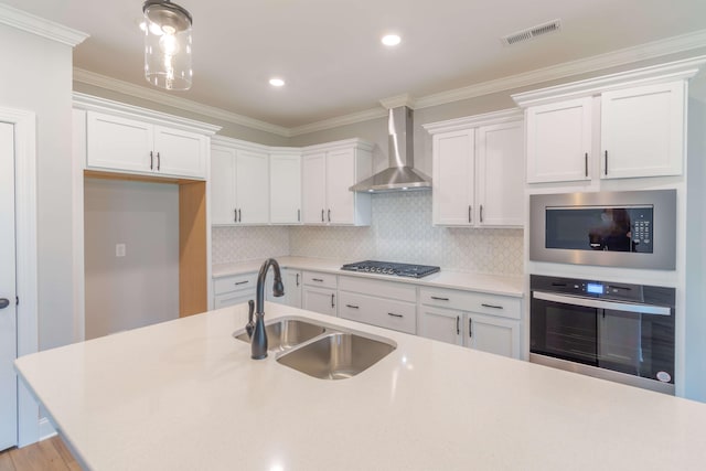 kitchen with white cabinets, appliances with stainless steel finishes, wall chimney range hood, and sink