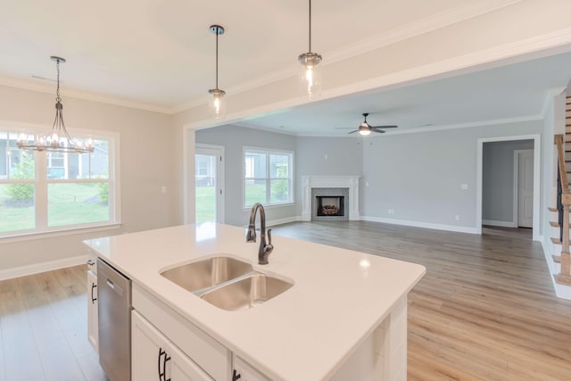 kitchen with white cabinets, an island with sink, dishwasher, a fireplace, and light hardwood / wood-style floors