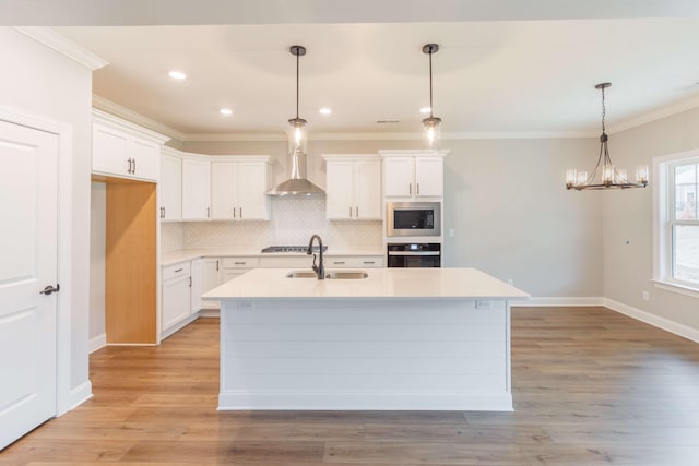 kitchen featuring appliances with stainless steel finishes, an island with sink, white cabinets, light hardwood / wood-style flooring, and sink