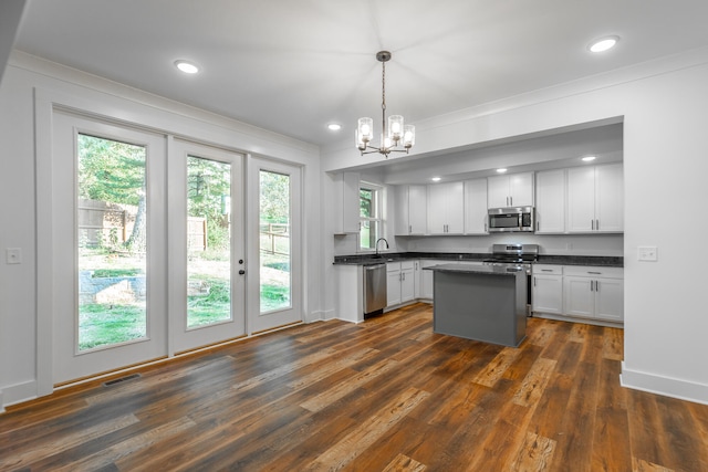 kitchen featuring dark wood-type flooring, appliances with stainless steel finishes, pendant lighting, and white cabinets