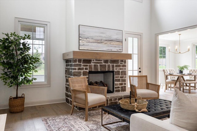 living room with wood-type flooring, a notable chandelier, and a stone fireplace