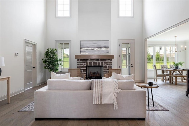 living room featuring a high ceiling, a notable chandelier, wood-type flooring, and a fireplace