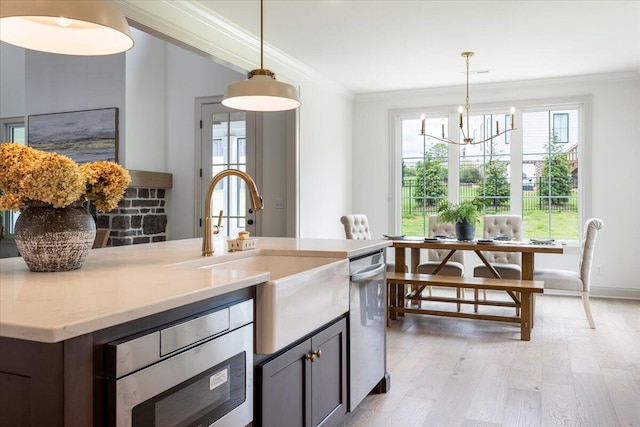 kitchen with hanging light fixtures, an inviting chandelier, light hardwood / wood-style floors, sink, and ornamental molding