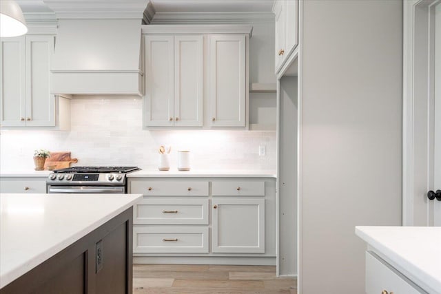 kitchen featuring light wood-type flooring, white cabinets, premium range hood, and gas stove