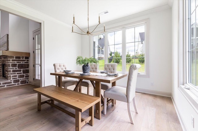 dining area with a fireplace, hardwood / wood-style flooring, crown molding, and a healthy amount of sunlight