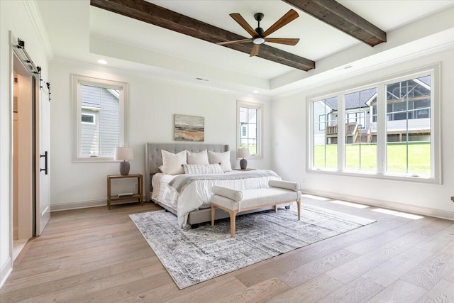 bedroom with a barn door, ceiling fan, beam ceiling, and light hardwood / wood-style flooring