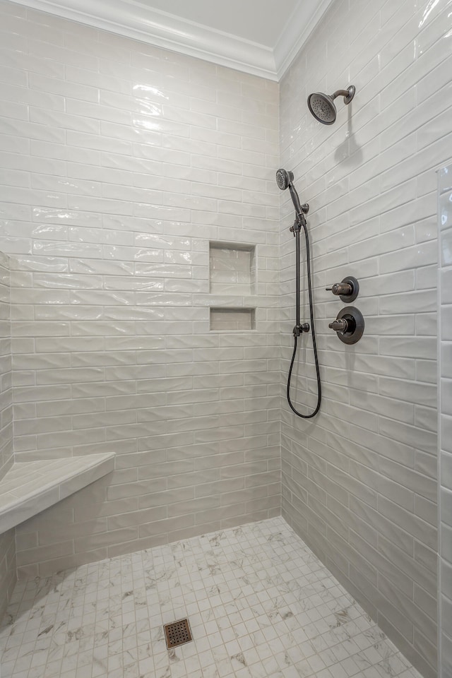 bathroom with a tile shower and crown molding