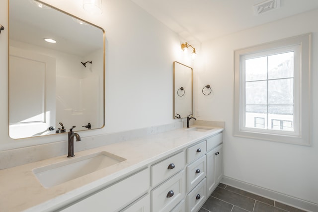 bathroom featuring a shower, a healthy amount of sunlight, tile patterned flooring, and vanity