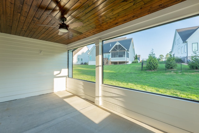 unfurnished sunroom featuring ceiling fan, a wealth of natural light, and wood ceiling