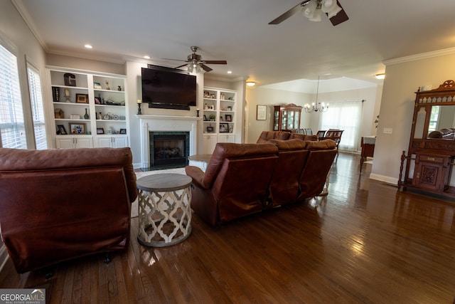 living room featuring ceiling fan with notable chandelier, dark hardwood / wood-style flooring, and ornamental molding