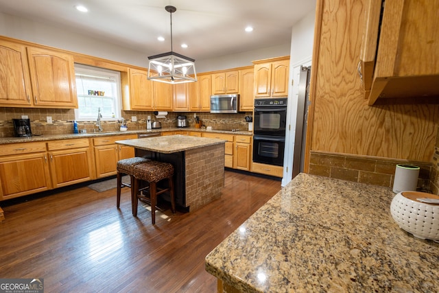 kitchen featuring dark hardwood / wood-style floors, black double oven, a center island, hanging light fixtures, and a chandelier