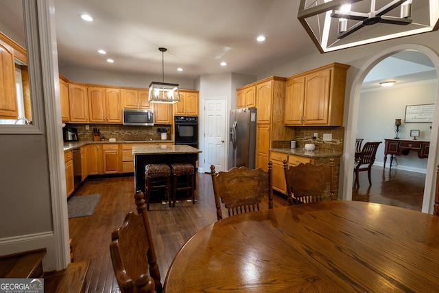 kitchen featuring a chandelier, a kitchen island, dark wood-type flooring, hanging light fixtures, and appliances with stainless steel finishes