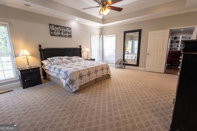 bedroom with a tray ceiling, light carpet, ornamental molding, and ceiling fan