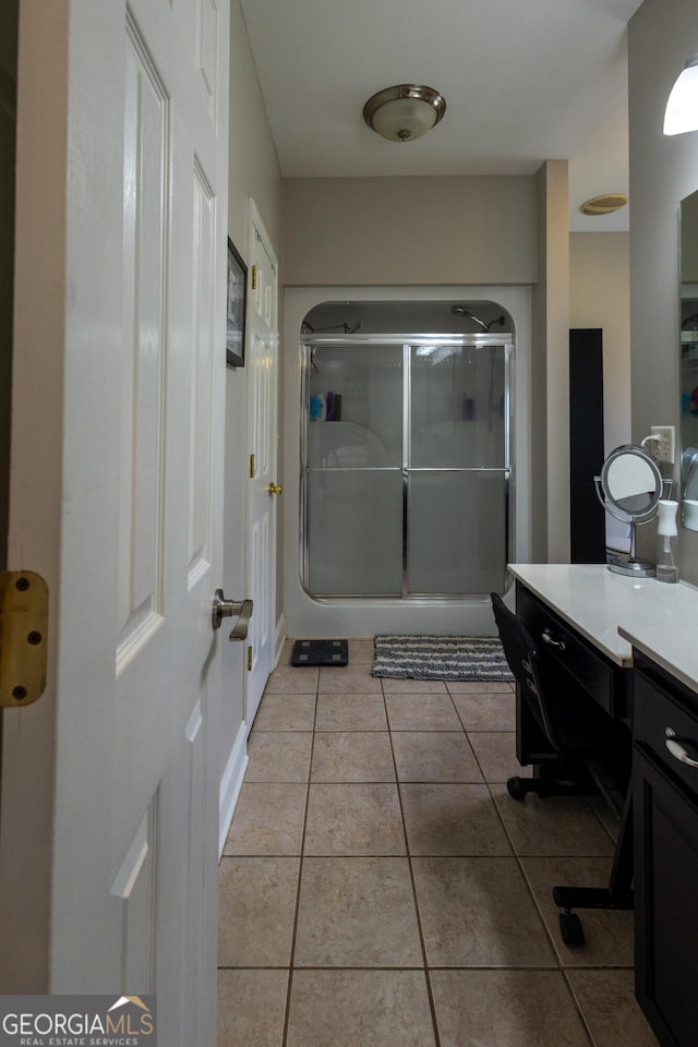 bathroom featuring a shower with door, vanity, and tile patterned flooring