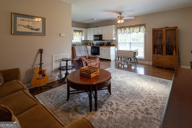 living room featuring ceiling fan and dark hardwood / wood-style floors