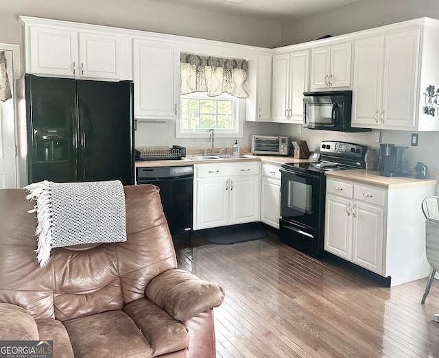 kitchen with black appliances, wood-type flooring, sink, and white cabinets