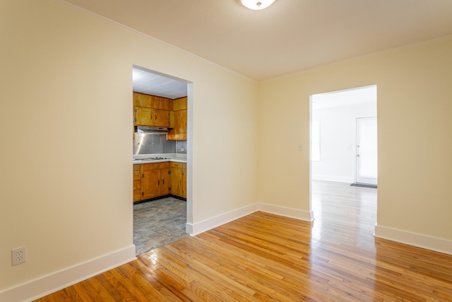 spare room featuring ornamental molding and light wood-type flooring