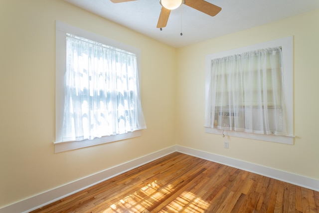 spare room featuring a wealth of natural light, wood-type flooring, and ceiling fan