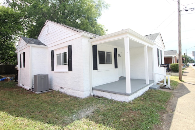 view of side of home featuring central air condition unit, a yard, and a porch