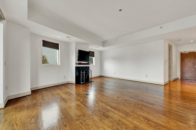 unfurnished living room featuring a tray ceiling and wood-type flooring