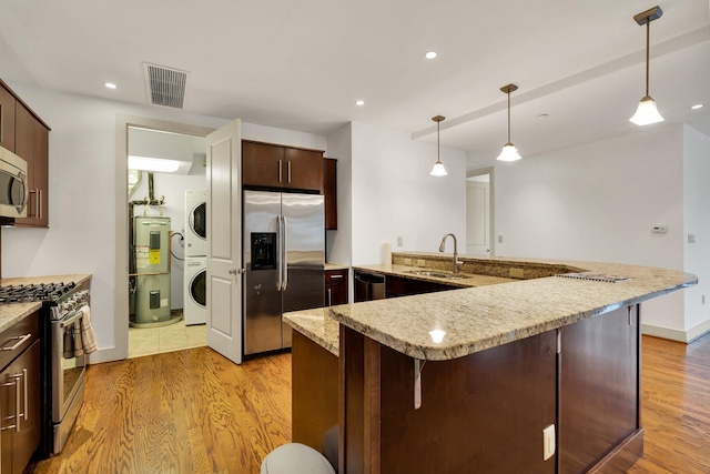 kitchen with stainless steel appliances, light hardwood / wood-style floors, sink, electric water heater, and stacked washer and dryer