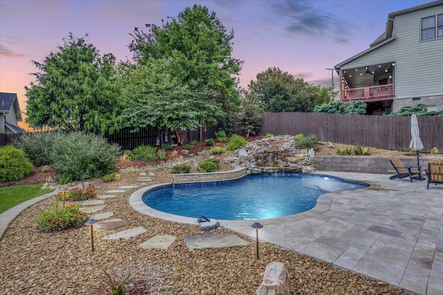 pool at dusk with pool water feature, ceiling fan, and a patio