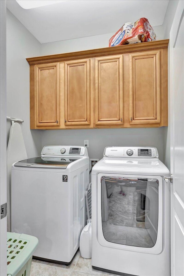 clothes washing area featuring washer and dryer and cabinets