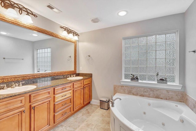 bathroom with a tub to relax in, tile patterned floors, and vanity