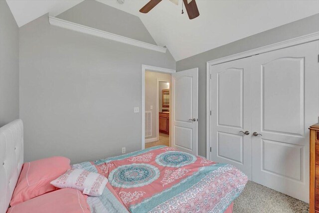 bedroom with ceiling fan, vaulted ceiling, light carpet, and a closet